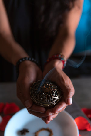 Close-up of hands lighting an incense, witch on the day of the dead performing a cleansing ritual, Halloween, spiritual beliefs, white magicの写真素材