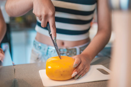 A home cook, she is cutting some delicious cheese in her kitchen, helping to prepare a delicious...