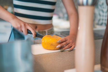 A home cook, she is cutting some delicious Dutch cheese in her kitchen, helping to prepare a...