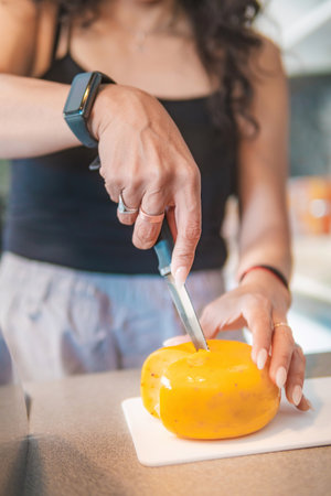 A home cook, she is cutting some cheese in her kitchen, helping to prepare a delicious breakfast.の写真素材