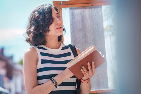 Young woman, take a book from a box of books on the street, she is standing on the sidewalk, these...