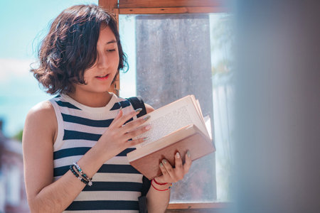 Young woman, take a book from a box of books on the street, she is standing on the sidewalk, these...