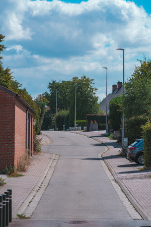Street in a village in Belgium, the street looks empty except for a single car parked in front of a...