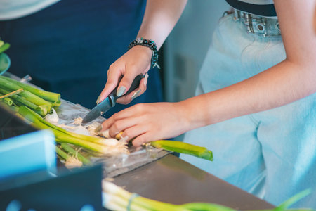 Two women whose hands can be seen arranging and cutting chives, are in the kitchen of their home.