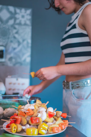 Red pepper, mushroom, and potato skewers; woman preparing skewers for lunch. Homemade food concept.の写真素材