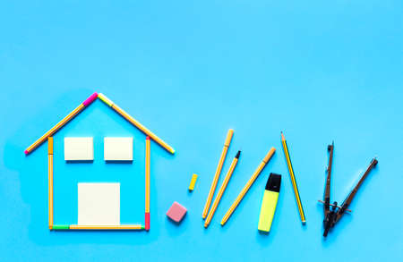 Top view of fluorescent marker pens forming a drawing of a house and other stationery materials on pastel blue background, space for text. Design and interior design concept.の写真素材