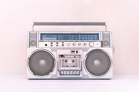 80's retro cassette radio in silver colour on light wood background. Play music concept.の写真素材