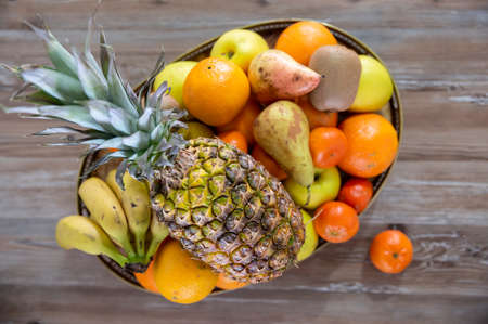 Top view of mixed fruit in basket on aged wooden board. Concept of food, fitness and health.の写真素材