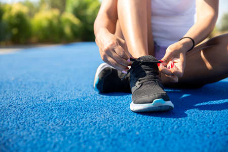 Close-up of a sportswoman tying her shoe laces before running. Space for text. Selective focus....