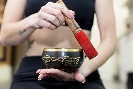 Close up of unrecognizable woman making sound with Tibetan bowl. Relaxation concept.の写真素材