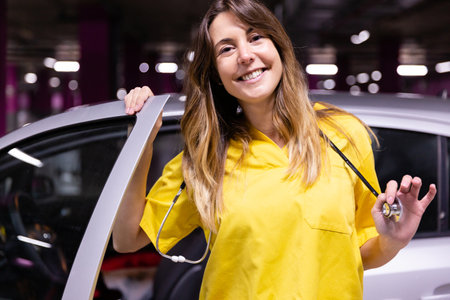 Portrait of young smiling female nurse getting out of her vehicle ready to start work. Space for text.の写真素材