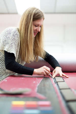 Portrait of a Caucasian woman marking with chalk on fabric a piece to be cut. Space for text.