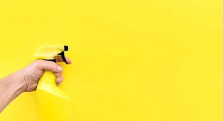 Close up of person's hand with cleaning sprayer isolated on yellow background. Space for text.の写真素材