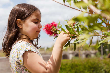 Close up portrait of little Caucasian child contemplating a flower in the open air. Space for text.の写真素材