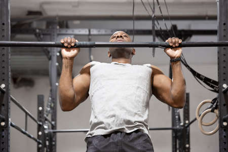 African American sportsman doing physical exercise on fixed bar. Fitness training in gym.の写真素材