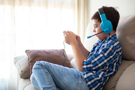 Caucasian adolescent boy playing online video games from home. Space for text.