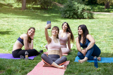 Group of young caucasian women taking a photo during an outdoor yoga class. Space for text.の写真素材