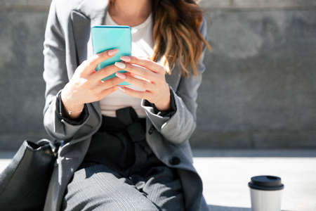 Unrecognizable business woman using her mobile phone outdoors. Space for text.の写真素材