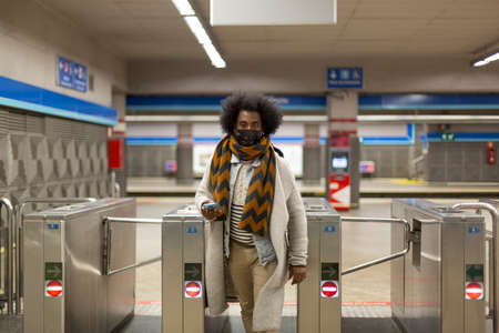 Young African American male wearing face mask exiting a subway station. Space for text.の写真素材