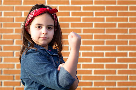 Little girl in clothing representative of working woman isolated on brick wall. Space for text.の写真素材