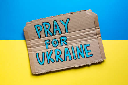Hand drawn sign with Pray For Ukraine slogan on Ukrainian flag.の写真素材
