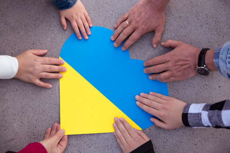 Human hands around a heart with the colors of the Ukrainian flag. Unity, solidarity and support for Ukraine. Not to war.の写真素材