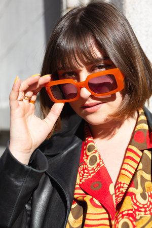 Portrait of young caucasian woman with short hair looking at camera lowering sunglasses. Modern style and feminine fashion concept. Close up.の写真素材