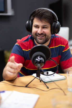 Portrait of smiling young caucasian man with headphones working in radio station. Announcer, commentator, live broadcast.の写真素材