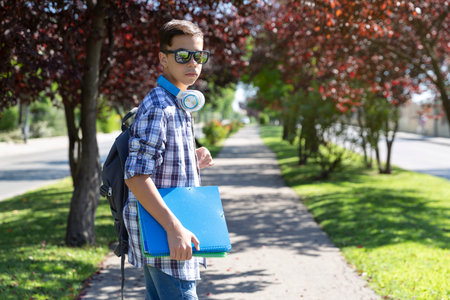 Caucasian teenage student boy with backpack going to high school. Secondary education. Space for text.の写真素材