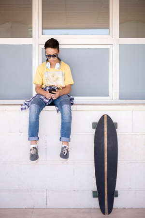 Caucasian teenage skater boy using mobile phone outdoors. Space for text.の写真素材