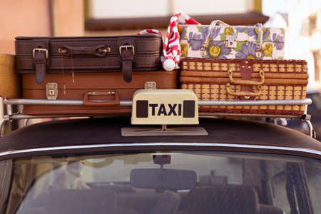 Detail of a taxi vehicle with several suitcases on the luggage rack. Retro style, 70s and 80s. Concept of tourism and holiday travel.の写真素材