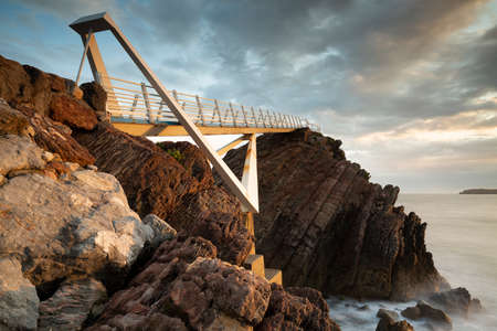 Seascape view of the long walkway of Las Gaviotas viewpoint located in Castrillon, Asturias, Spain. Cloudy day.の写真素材