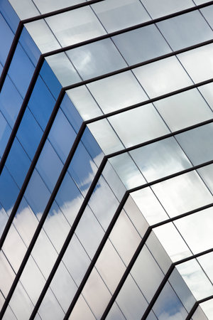 Part of a modern office building with the sky reflected in its mirrored glass panes.の写真素材