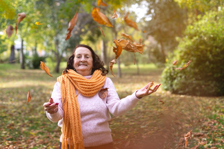 Happy caucasian elderly woman enjoying an autumn day in nature. Space for text.の写真素材