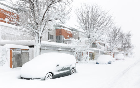 Residential street completely snowed in with snow-covered cars parked at the entrance to the houses. Winter scenery. Space for text.の写真素材