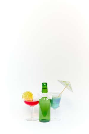 Set of empty green glass beer bottle with two equally empty transparent glass goblets on white background. Copy space. Portrait photography.の写真素材