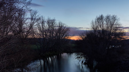 View of a river at dusk reflecting a dramatic sky. Panoramic format.