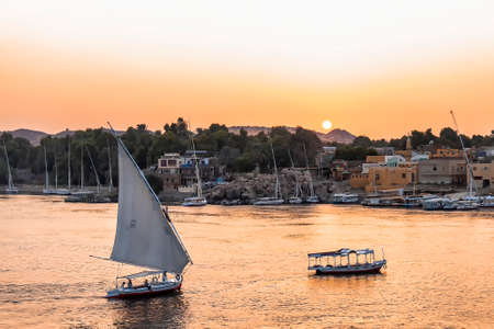 Felucca boat sailing on the Nile river at sunset in Aswan, Egypt