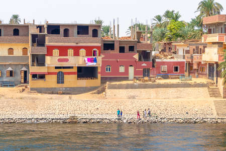 Aswan, Egypt - September 13, 2018: Children waving to Nile Cruise tourists next to the Nile River, southern Egyptの写真素材