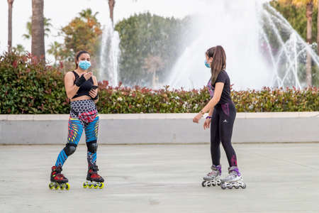 Huelva, Spain - May 3, 2020: Young women roller-skating in the park and wearing a protective mask...