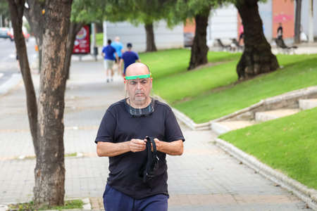 Huelva, Spain - May 6, 2020: Man going out for a walk wearing Medical face masks or shields, transparent plastic helmet during the alarm state and quarantine in Spain.のeditorial素材