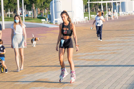 Huelva, Spain - May 23, 2020: Young women practicing roller-skating in Huelva promenade at sunset. She has a protective mask attached to her waist in case she needs it.のeditorial素材