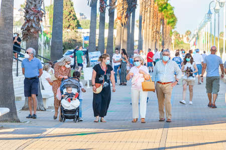 Huelva, Spain - June 3, 2020: People walking by Islantilla promenade at sunset wearing protective mask due to covid-19.のeditorial素材