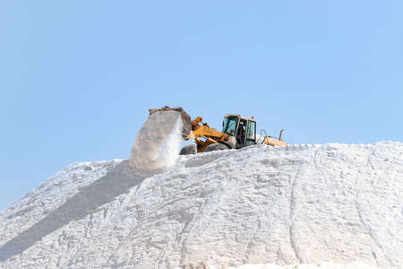 Huelva, Spain - October 1, 2020: Excavator working in a huge pile salt at saltworks in Marismas del Odiel. Marine salt produced by the evaporation of seawater.のeditorial素材