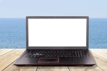 Black laptop over a table in the beach as concept for teleworking, telework, telecommutingの写真素材