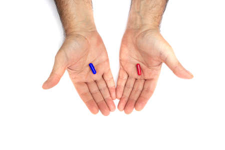 Red and blue pills on hand isolated on white background. They represent the choice between embracing...