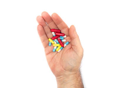 A man hand with multiple colors pills on white background, concept for take your medication