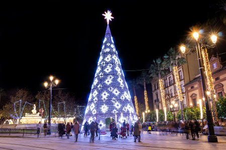 Seville, Spain - December 21,2020: Long exposure photography of Christmas tree in Puerta de Jerez, next to Seville Cathedral, at christmas time. People blurred by movementのeditorial素材