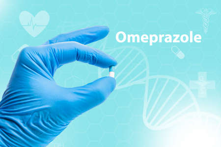 Hand of doctor or nurse with a capsule of Omeprazole. Omeprazole is used to treat certain stomach...