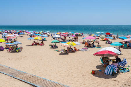 Chipiona, Cadiz, Spain - June 13, 2021: Chipiona beach full of tourists with umbrellas enjoying a sunny dayのeditorial素材
